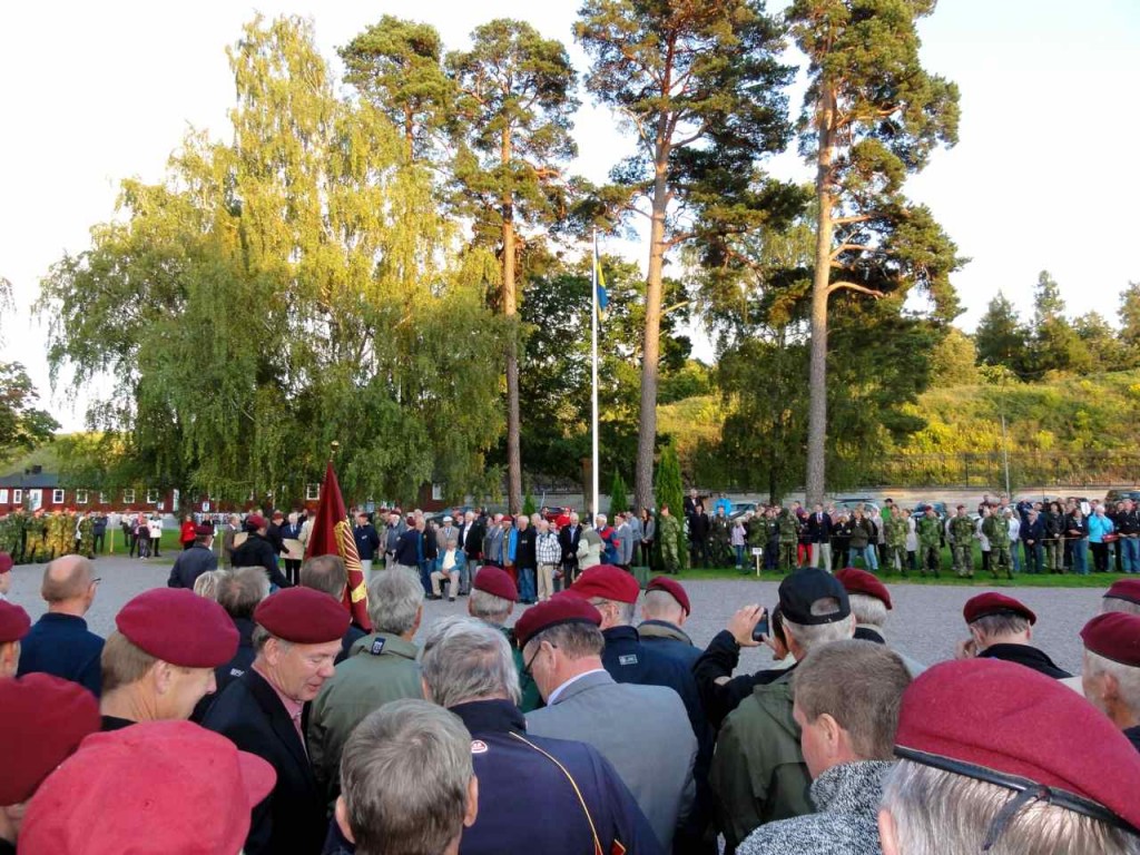 Jubilarerna från årskurs 52/53 skymtas när de är uppställda framför podiet.